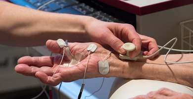 Foto: Detailszene: Elektroden werden an der rechten Hand eines Patienten oder einer Patientin befestigt.