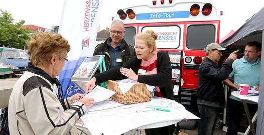 Foto: An einem Informationsstand im Freien lassen sich Patienten beraten. Im Hintergrund steht ein Infomobil.