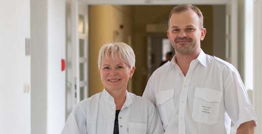 Foto: Eine Ärztin und ein Arzt blicken freundlich in die Kamera